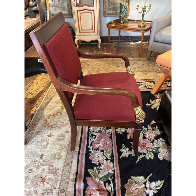 Classic Empire style armchair having walnut frame with gilded dolphins on the arms and cranberry upholstery. Duffy