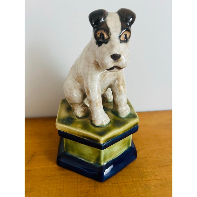 Large pottery trinket box with dog, Jack Russel Terrier sitting on top. Box is painted green and navy blue. I’m not sure...