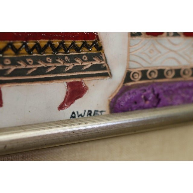 Vibrantly colored, textured original Mid-Century framed tile art, handcrafted by Irene Awret. A central figure holds a...