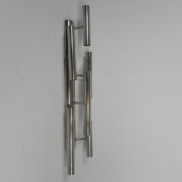 This wall lamp consists of 6 cylinders Ø 2.8 cm. Lengths: 2x25 cm, 2x20 cm, and 2x15 cm. The lamp looks best with mirrored...