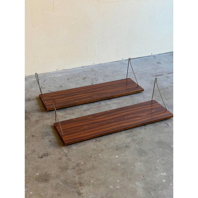 Danish Mid-Century Modern floating shelves crafted in richly grained rosewood with original brass wire wall brackets....