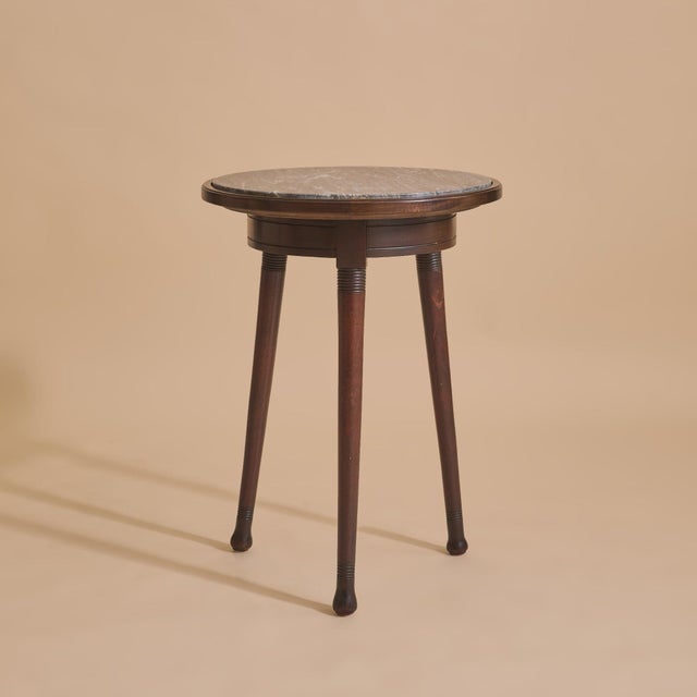 An early 20th century French guéridon table, crafted in dark-stained wood and crowned with a marble top. The circular...
