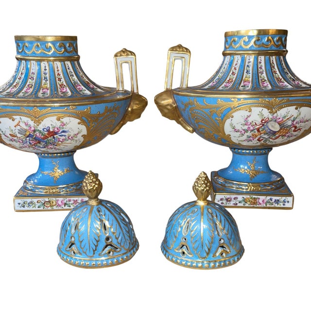 Decorative pair of French Sèvres style porcelain urns in a rich celestial blue ground with gilt decoration and hand-...