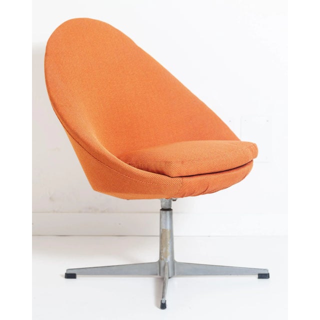 This swivel chair is upholstered with fabric and stands on a metal cross base.