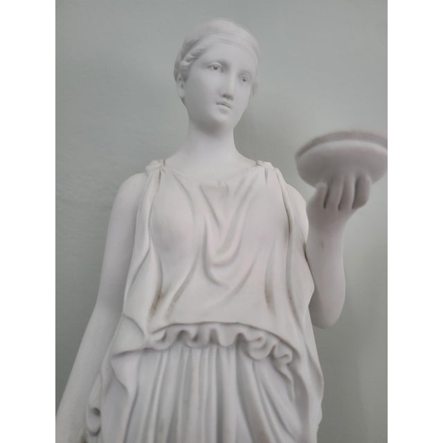 An elegant vintage mid-20th-century neoclassical reproduction figurine depicting Hebe, the Greek Goddess of Youth and...