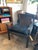 The L1888-01 armchair features a black leather sling-style back and arm panels secured with brass rivet detailing. The...