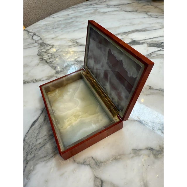 Decorative box features a sleek rectangular body crafted from rich red marble, showcasing natural veining and an elegant...