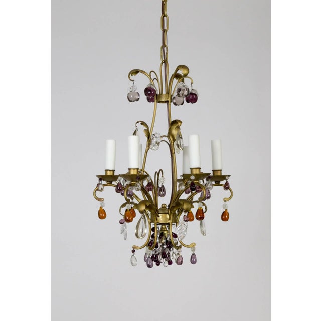 A gilt brass chandelier with dangling crystal fruit in amber, purple, amethyst, and clear. Apples hang from the crown and...