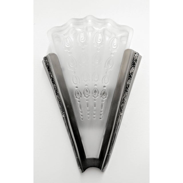 A pair of French Art Deco sconces. Fan-shaped design in clear frosted glass shades with details throughout. Shades rest on...