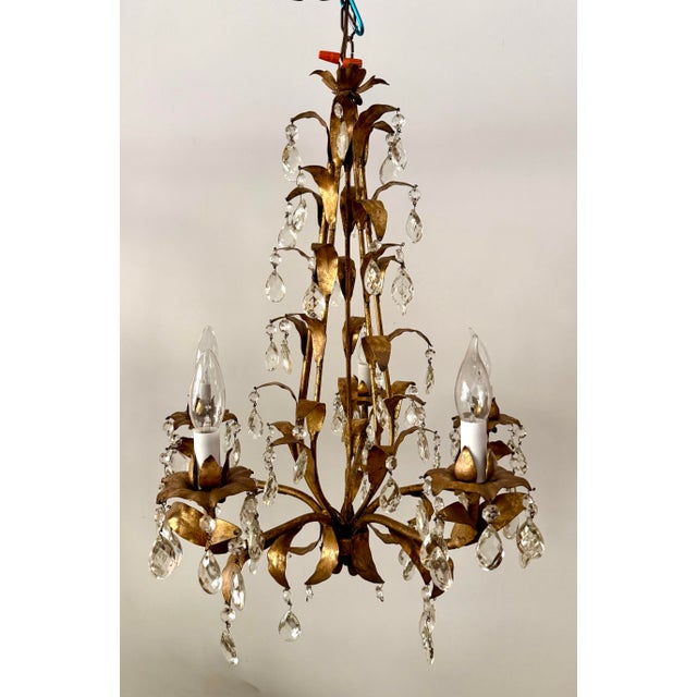 Here is a vintage mid-20th century three-light chandelier featuring sculptural gilt metal foliage and cascading faceted...