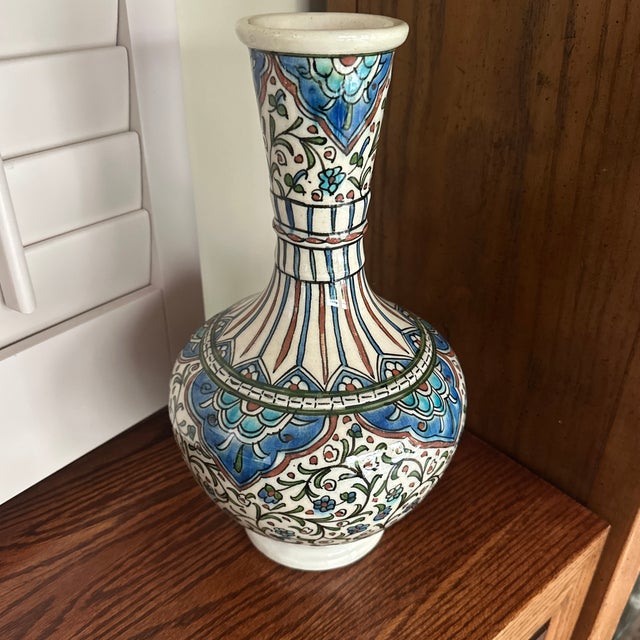 This is an Iznik-style ceramic vase, featuring traditional Ottoman motifs. Iznik pottery originates from the town of İznik...
