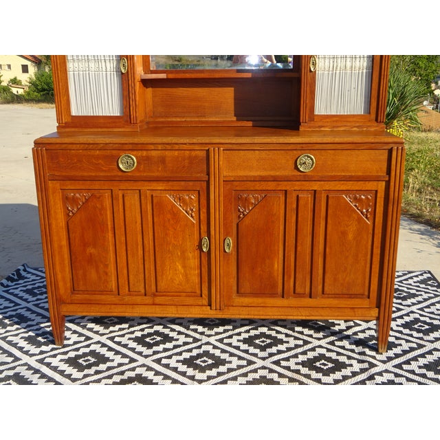 A two-door, two-drawer sideboard surmounted by two small cabinets framing a mirror. The glass-fronted cabinets feature...