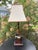 Charming vintage table lamp featuring a hand-painted duck perched at the base of a warm wood-tone column. The sculptural...