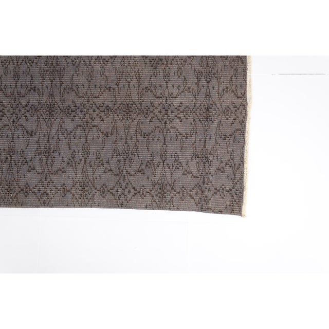 This is a vintage Turkish Oushak rug from the Mid 20th Century. The piece was hand-knotted.