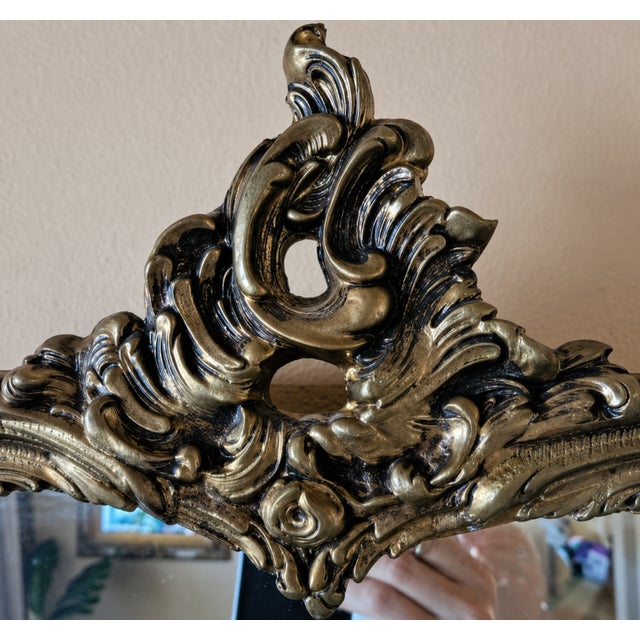 Elegant vintage ornate wall mirror featuring a beautifully sculpted rococo-inspired frame with intricate scrolling details...