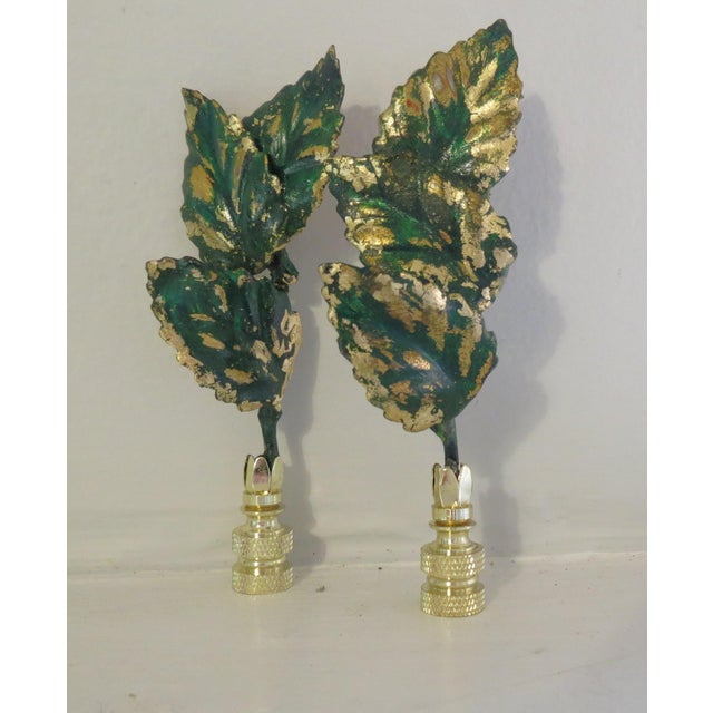 Unique pair of vintage Italian Gold Leaf Tole Finials set in brass bases. Triple set of leaves reaches upward to reflect...