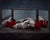 This oil on panel artwork presents a striking still life featuring animal skulls delicately arranged with vibrant red...