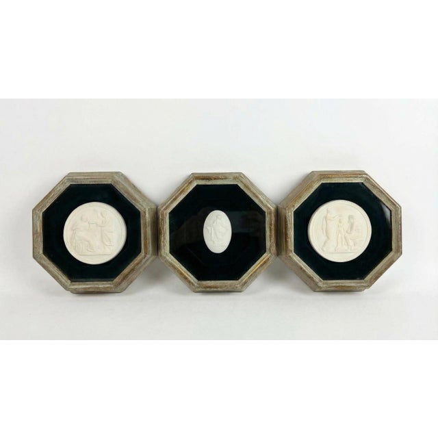 This rare mid-century hinged triptych features three neoclassical scenes rendered in white plaster relief, each mounted on...