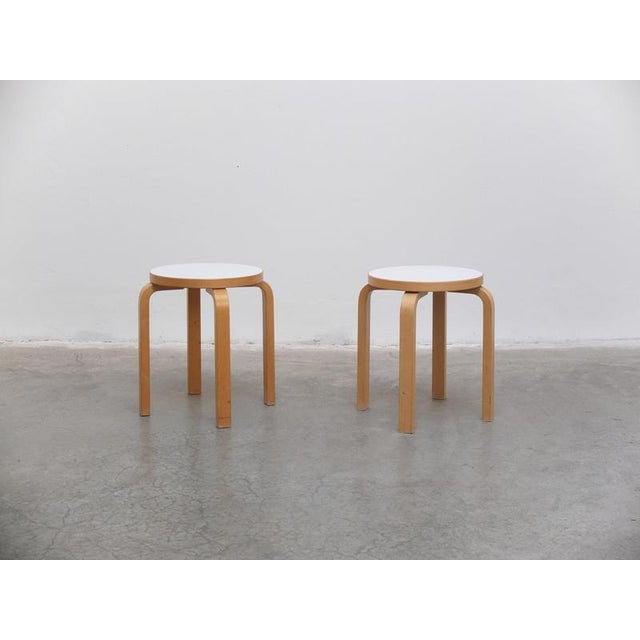 Iconic pair of ‘E60’ stools designed by Alvar Aalto in 1933. Made of birch wood with a beautiful white lacquered seat....