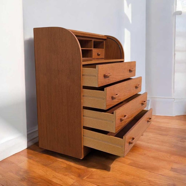 A compact Danish modern teak roll-top desk by Egon Ostergaard, dating to the 1970s. The tambour front conceals a fitted...