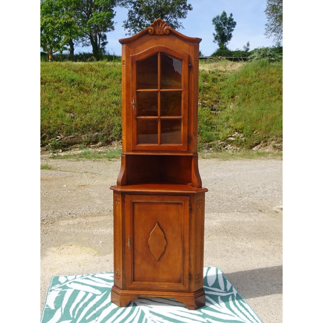 Small, tall, and narrow corner cabinet composed of two parts: a corner sideboard with one cupboard door topped by a...