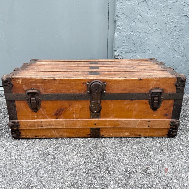 A character-rich antique wooden trunk featuring a desirable low-profile, flat-top form with warm aged wood and substantial...