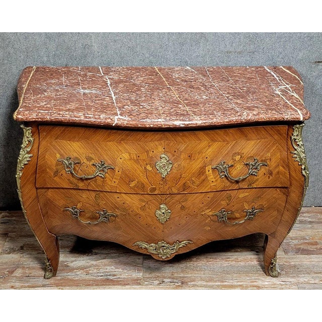 A Louis XV style marquetry commode with a curved front, circa 1850. The front opens with two drawers without a central...