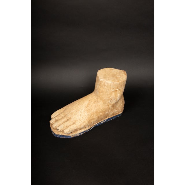 This large carved wooden foot showcases a stylized representation of the human form, with a focus on simplicity and an...