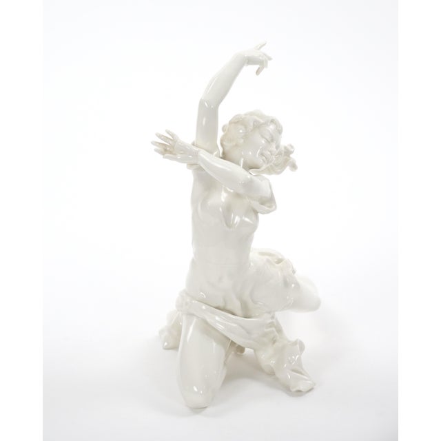 This elegant Art Deco white glazed porcelain sculpture depicts a graceful female dancer captured in a dramatic and highly...