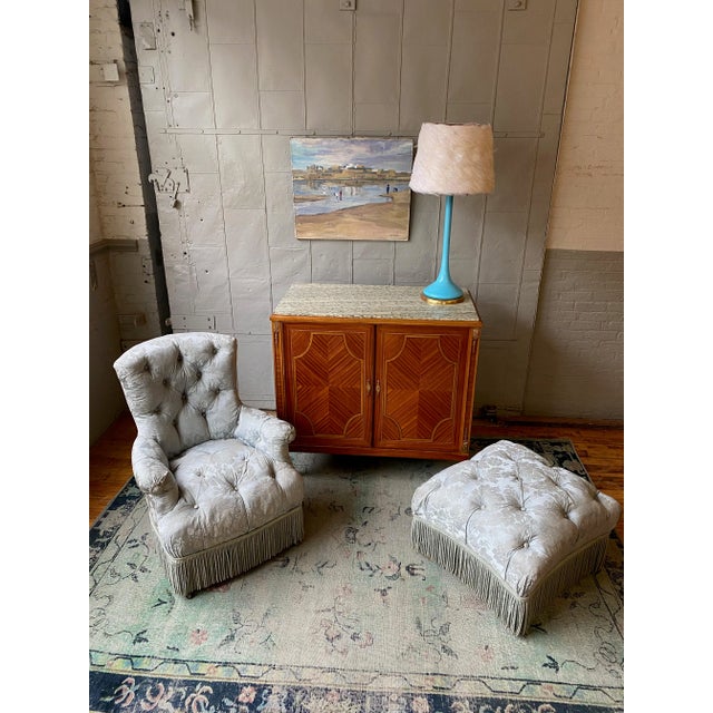 A wonderfully proportioned 19th century French tufted armchair with a matching ottoman, upholstered in light blue silk...