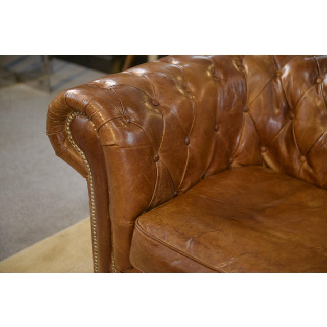Chesterfield sofa in brown leather with deep button tufting. Enveloping silhouette with rolled armrests and a three-...