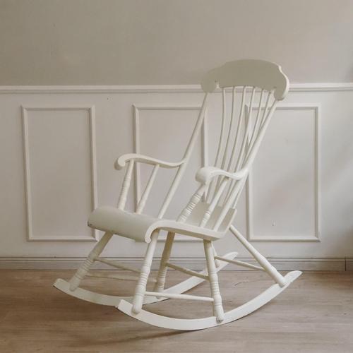 A white lacquered rocking chair in the style of Windsor, dating from the mid-20th century. The high back with its slender...