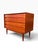 A Danish modern four-drawer dresser in richly figured teak, by Arne Vodder. Full-width sculpted pulls are carved directly...