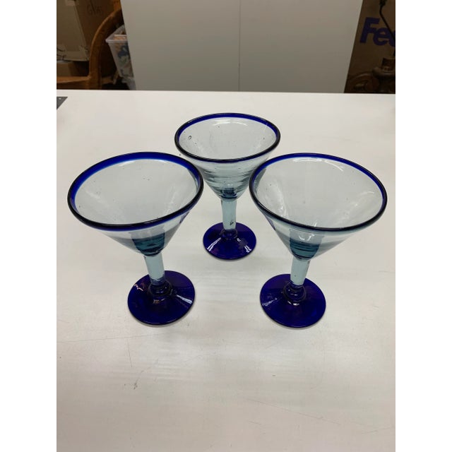 These are hand blown Martini or Margarita Cocktail Glasses. They are mostly transparent with the rim and base being a dark...