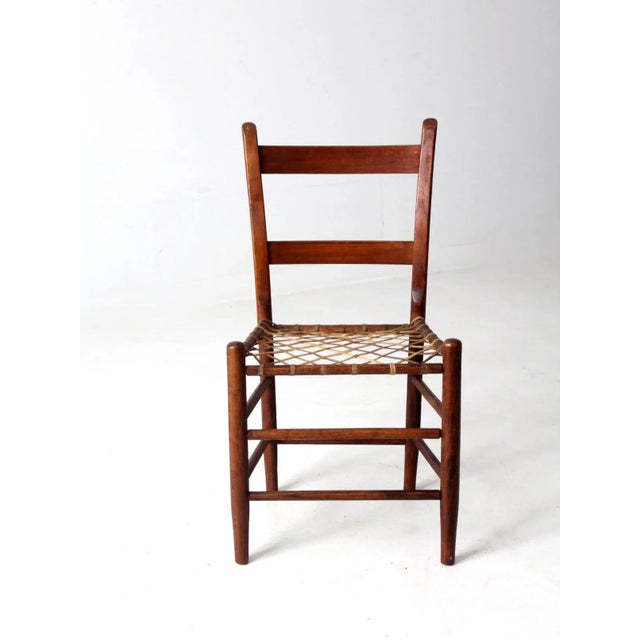 This is a 19th century antique primitive chair with rawhide seat. The handmade wooden chair features a ladder back and...