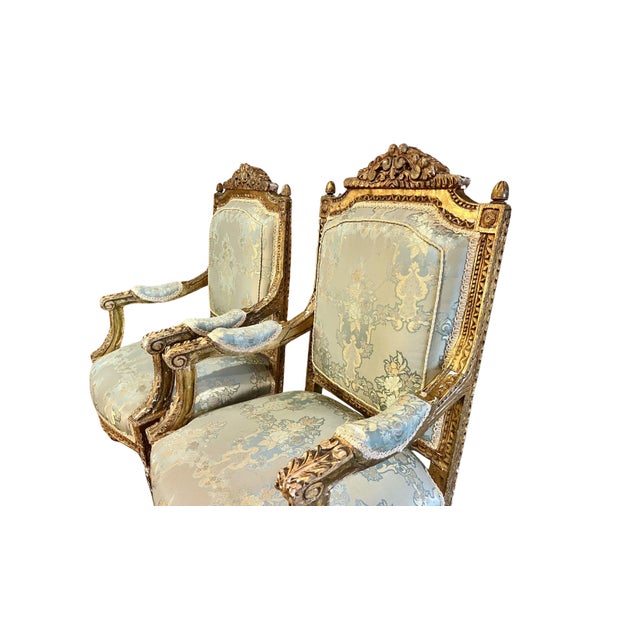 Elegant pair of Louis XVI style giltwood fauteuil armchairs featuring finely carved frames with classical ornamentation...