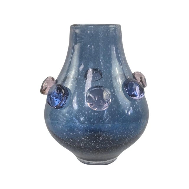 The softly tapered silhouette features a rich blue tone enhanced with delicate bubble detailing within the glass. Raised...
