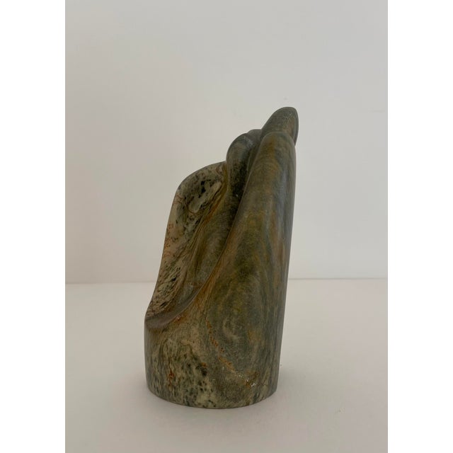 Hand carved stone sculpture with shades of green, brown and tan. Artist signed.