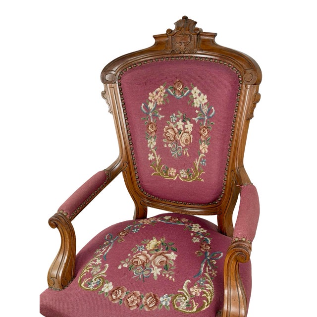 A vintage Renaissance Revival-style armchair pairing a carved wooden frame with burgundy floral upholstery. The tall back...