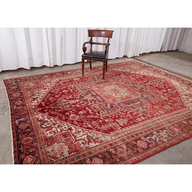 Traditionally styled vintage Persian Heriz rug crafted from hand-knotted wool. The rug features a large multi-faceted...