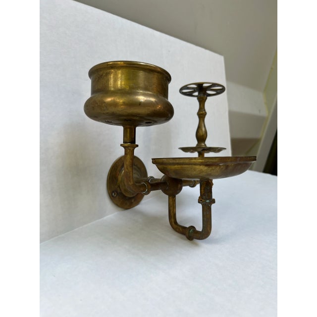 A single antique brass wall mounted articulating bathroom accessory holder including a tumbler or cup holder, toothbrush...