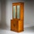 Very tall yet relatively narrow display cabinet with a two-door lower section and a glazed two-door upper case. The piece...