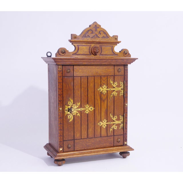 An antique small wooden cabinet with brass fittings and a beautiful carved lion head on top. The chest is hand made with...
