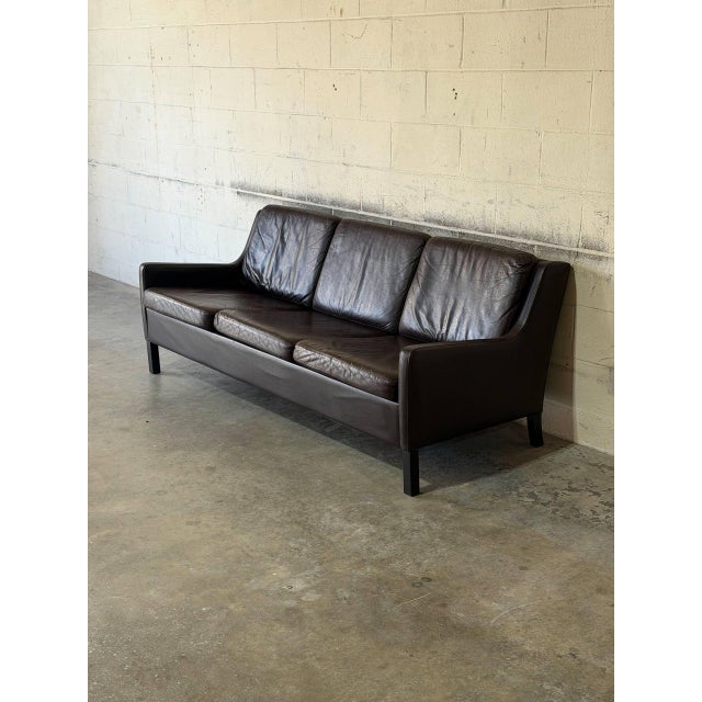 This three-seater sofa features a streamlined silhouette with subtly flared arms and plush removable cushions. It rests on...