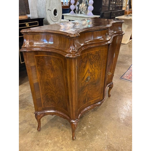 This 19th century Italian black walnut shaped front cabinet is a unique and stylish piece of furniture that would add a...