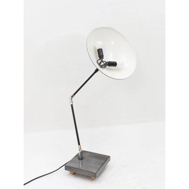 This metal desk lamp features a typical 1960s style shade/armature assembly mounted to an unusual square metal base on...