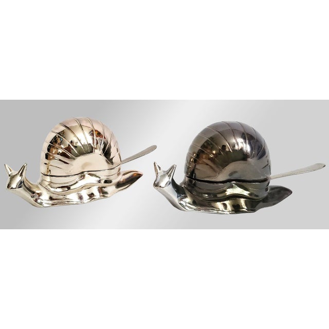 Offering a whimsical pair of silver plated snail salt cellars, circa Late 20th Century. One of the snails is a bright...