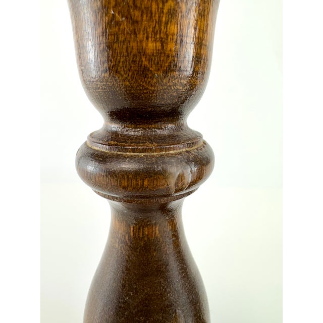 A pair of vintage turned wood candlesticks showcasing classic proportions and a warm walnut-toned finish that highlights...