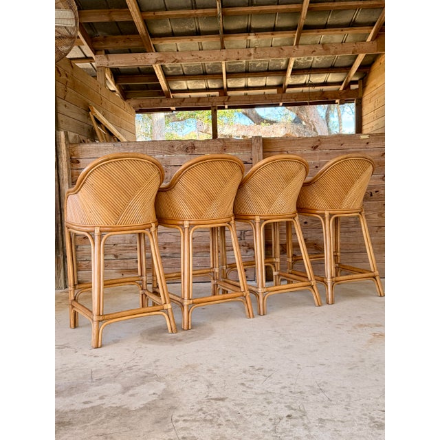 Striking set of four vintage Organic Modern rattan bar stools, beautifully crafted with sculptural curved frames, finely...