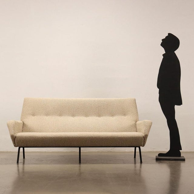 Three-seater sofa from the 60s with foam padding and new fabric upholstery with enamelled metal legs. This piece is...
